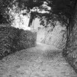 Analoges Schwarz-Weiß Foto zeigt einen alten gepflasterten Weg, der einen Berg hinauf führt