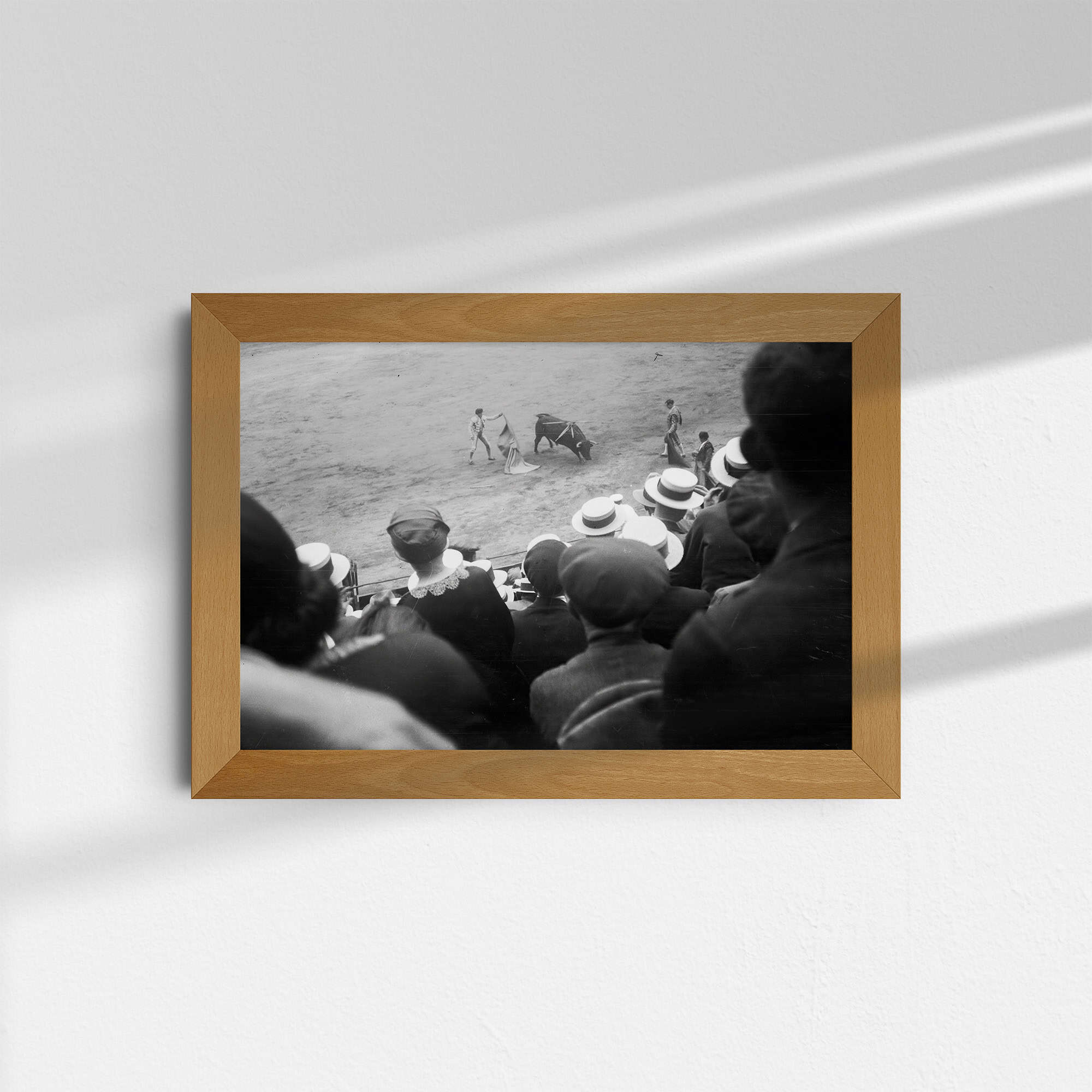 Dieses historische Schwarz-Weiß Foto zeigt einen Stierkampf (Corrida de Toros) in einer vollbesetzten Arena in Barcelona, Spanien. Das Foto wurde um das Jahr 1930 aufgenommen. Es zeigt Zuschauer in zeitgemäßer Kleidung, die drei Toreros beim Kampf mit einem Stier beobachten.