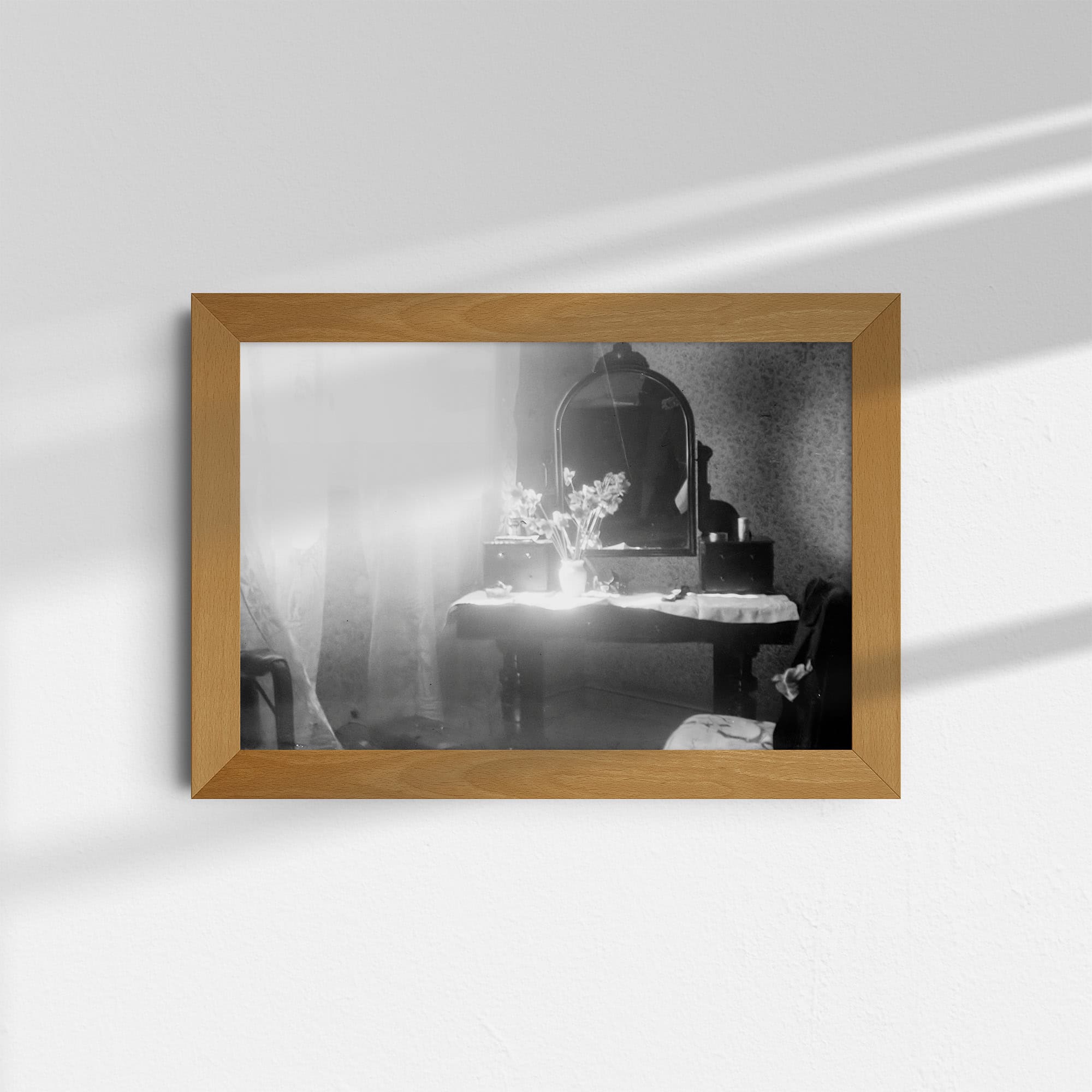 Dieses Schwarz-Weiß Foto zeigt einen alten Frisiertisch mit Spiegel, wie er in den 20er Jahren genutzt wurde. Auf dem Tisch steht eine Vase mit Blumen. Rechts ist ein Stuhl zu sehen, auf dessen Lehne ein Jackett hängt. Auf der linken Seite ist ein Fenster, durch das helles Tageslicht in das Zimmer fällt. Links unten sind Koffer zu sehen. Das Foto wurde wahrscheinlich in einem Zimmer des Hotels Ritz in Barcelona, Spanien, um das Jahr 1930 aufgenommen.