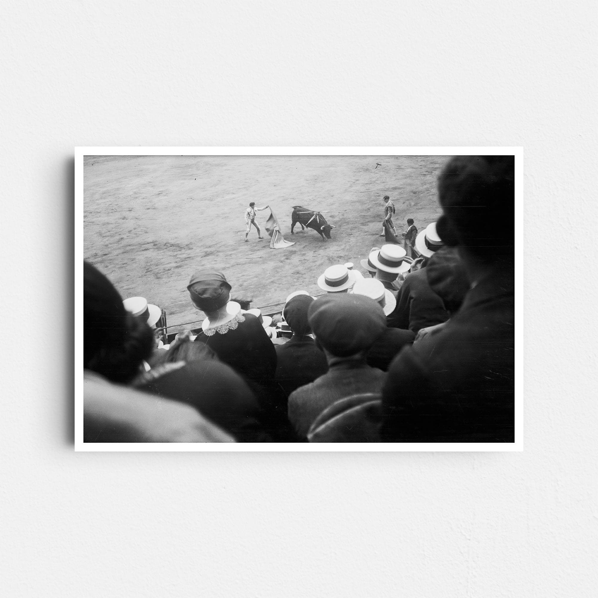 Dieses historische Schwarz-Weiß Foto zeigt einen Stierkampf (Corrida de Toros) in einer vollbesetzten Arena in Barcelona, Spanien. Das Foto wurde um das Jahr 1930 aufgenommen. Es zeigt Zuschauer in zeitgemäßer Kleidung, die drei Toreros beim Kampf mit einem Stier beobachten.
