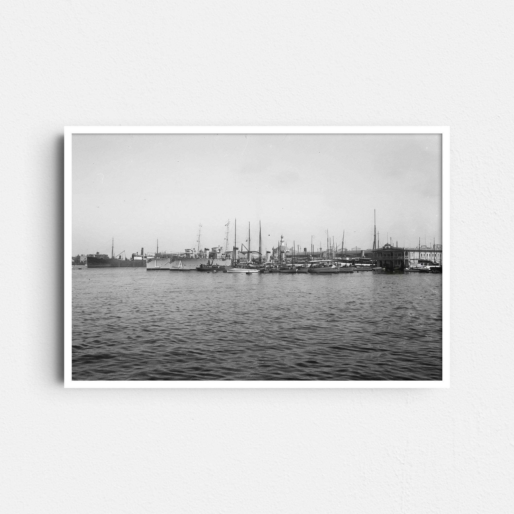 Dieses historische Schwarz-Weiß Foto zeigt einen Blick auf den Hafen von Barcelona, Spanien, um das Jahr 1930. Auf der linken Seite ist ein altes Frachtschiff zu sehen, auf der rechten Seite kleinere Boote. Das Zentrum wird von zwei Zerstörern der Spanischen Marine dominiert, der "Alsedo" und dem Schwesterschiff "Lazaga". Zusätzlich sind alte Gebäude des Hafens zu erkennen.